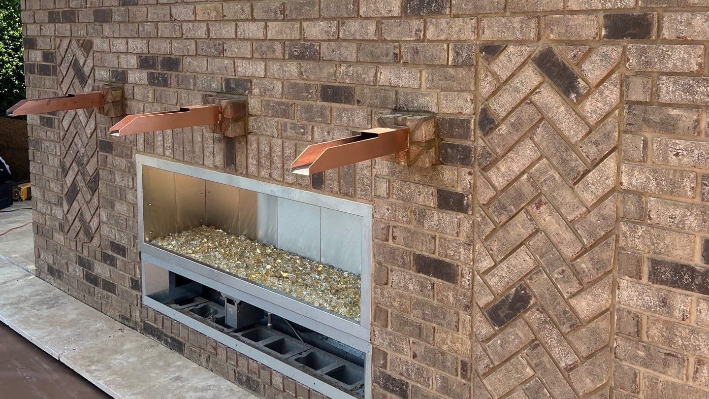 Brick outdoor feature wall with a linear gas fire burner and copper water spouts