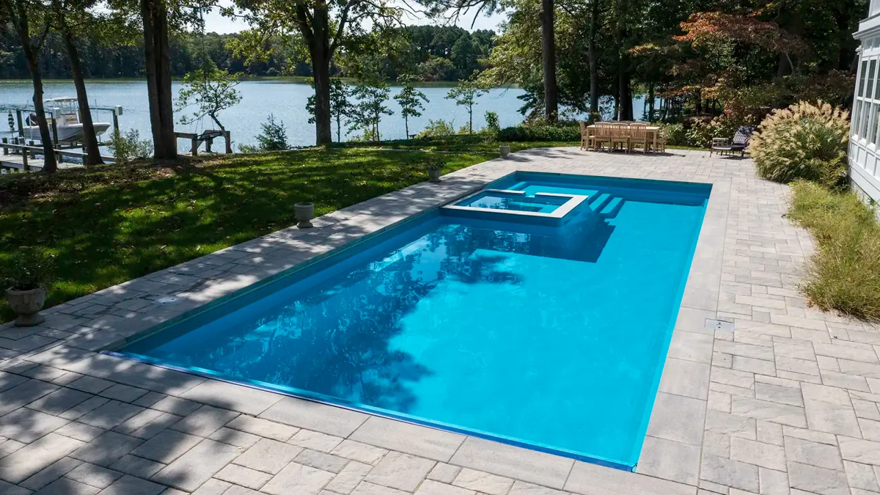 Lakefront fiberglass pool with a built-in spa and paver deck, installed by Morales Outdoor Living in East Tennessee