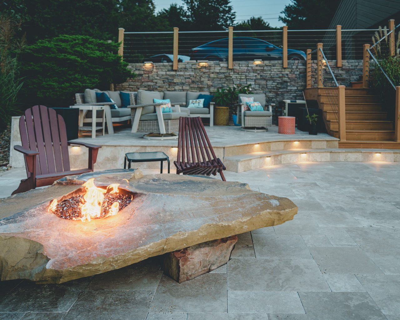 Lit Stone Fire Table & Travertine Lounge at Dusk