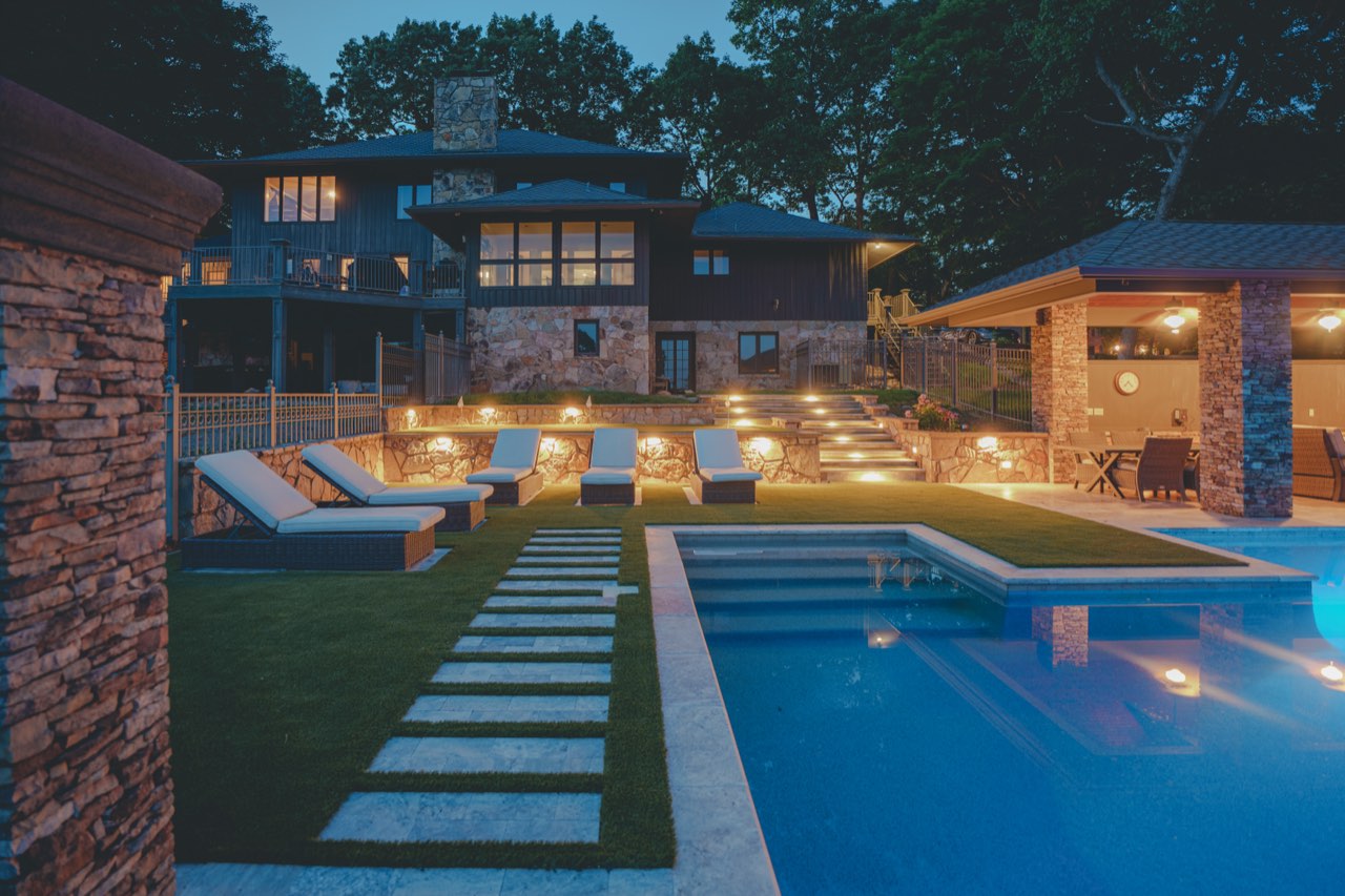 Dusk Pool With Lit Stone Steps & Paver Walkway