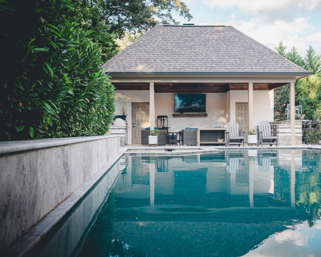 Pool Reflection of Pavilion Framed by Travertine Retaining Wall