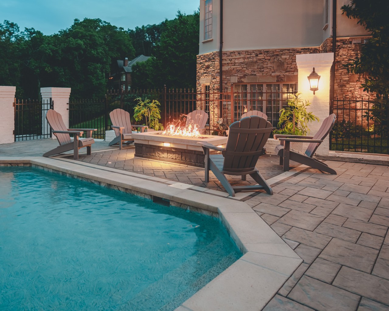 Poolside Fire Pit Lounge With Stone Veneer at Dusk