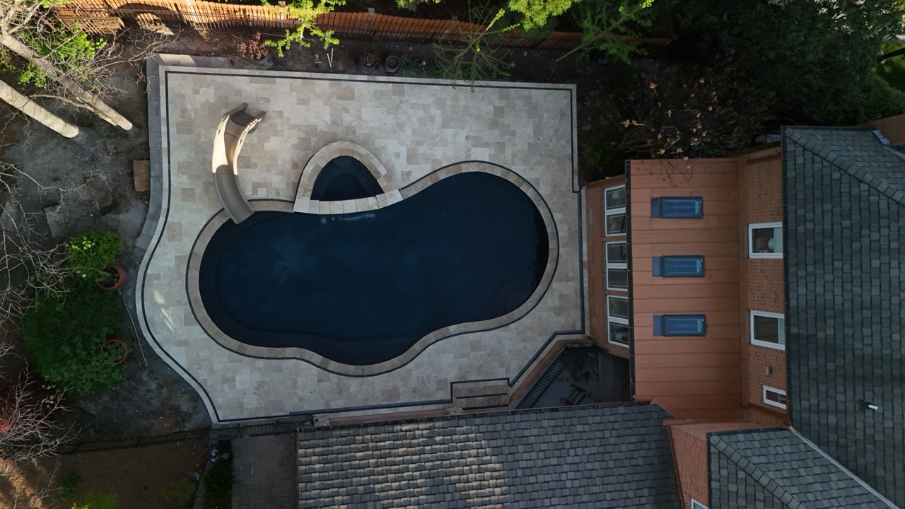 Aerial Freeform Gunite Pool With Travertine Deck and Slide