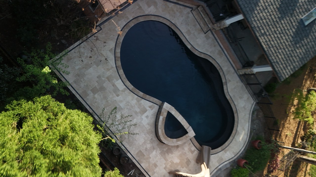 Aerial Freeform Pool, Curved Slide and Paver Deck Among Trees