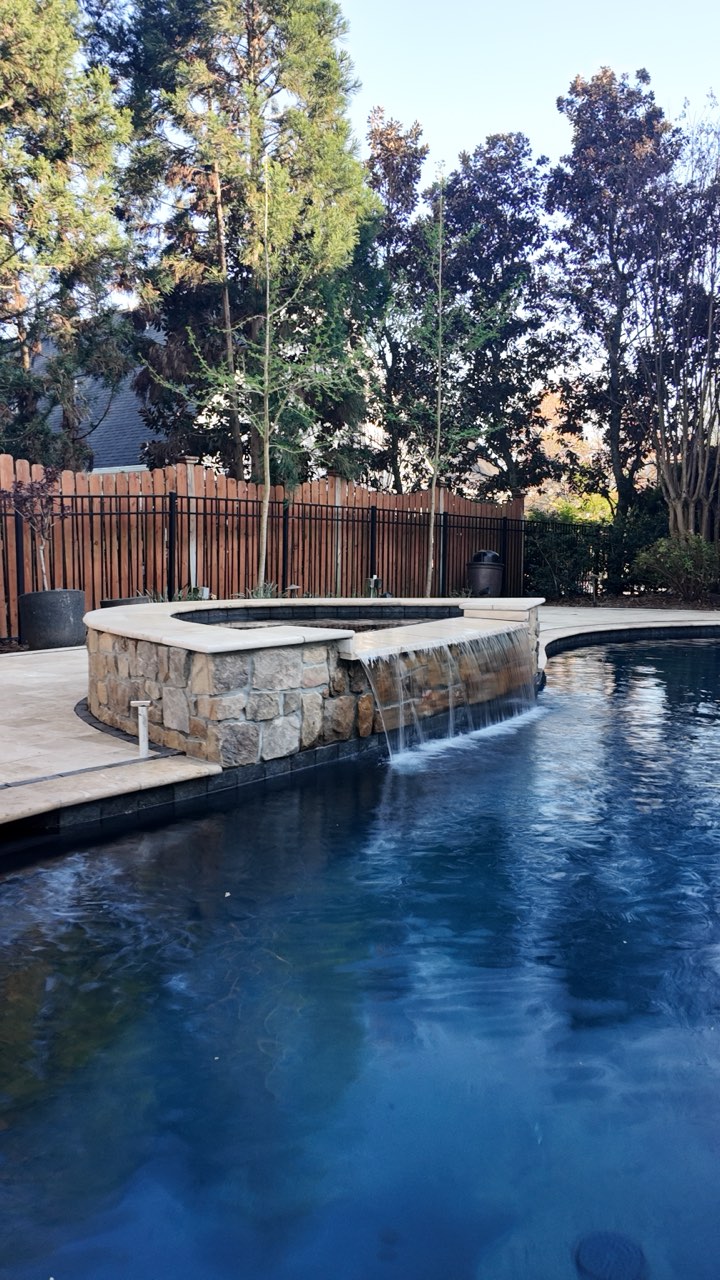 Raised Stone Spa With Sheer Descent Waterfall Into Pool